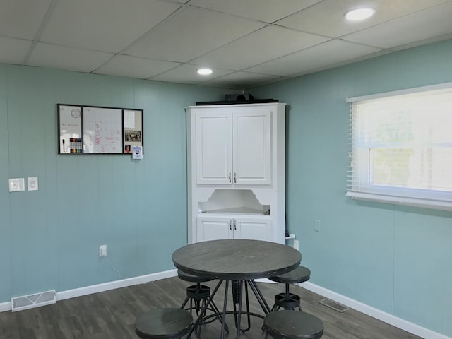 dining area featuring dark wood-type flooring, a paneled ceiling, visible vents, and baseboards