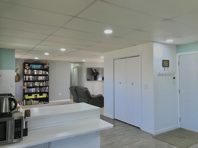 interior space with recessed lighting, wood finished floors, a paneled ceiling, and baseboards