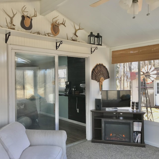 sunroom / solarium featuring lofted ceiling, ceiling fan, and a lit fireplace