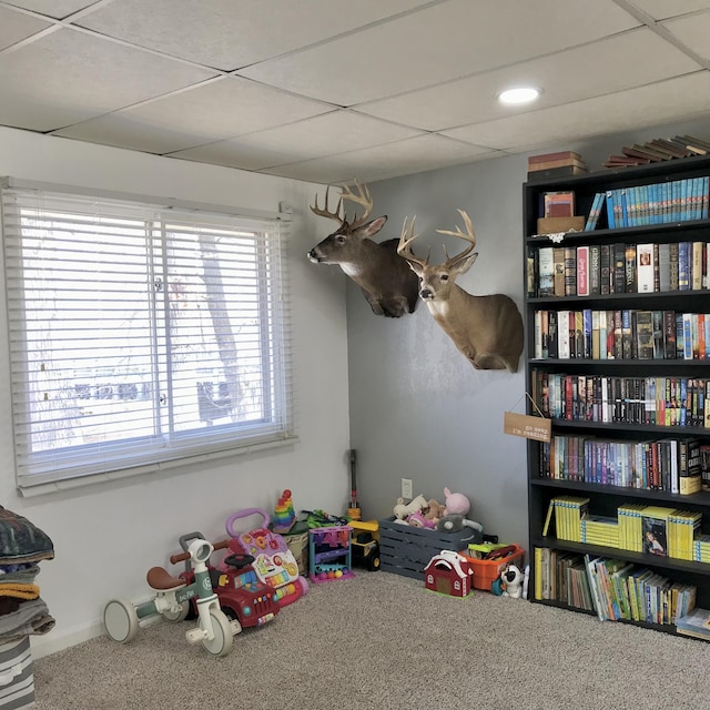 recreation room featuring a drop ceiling and carpet flooring