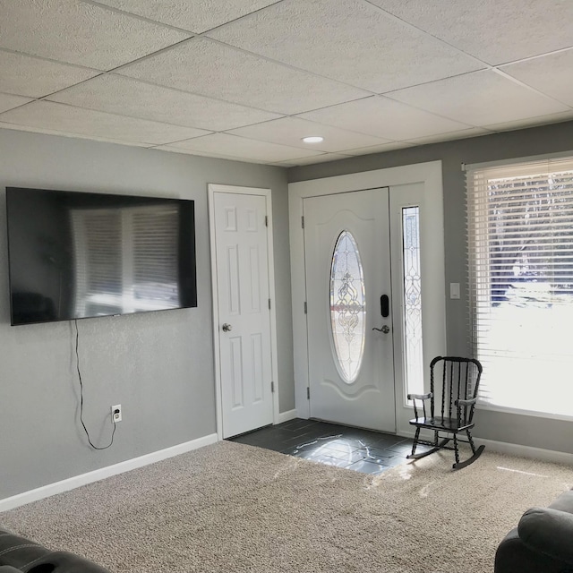 entryway featuring carpet flooring, a drop ceiling, and baseboards