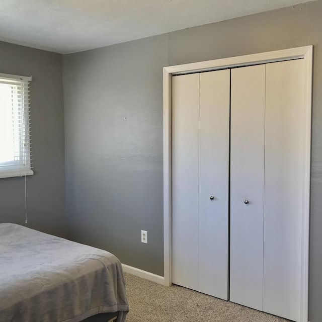 bedroom featuring a closet, light colored carpet, and baseboards