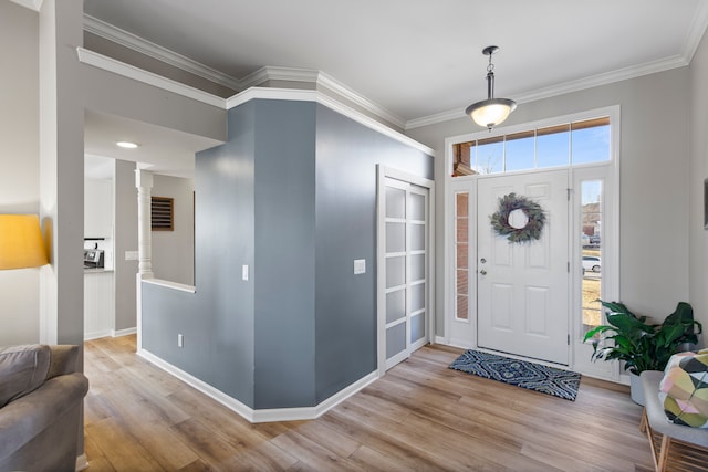 foyer entrance with crown molding, baseboards, and wood finished floors