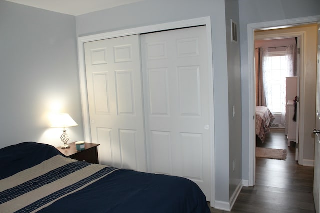 bedroom featuring a closet, visible vents, baseboards, and wood finished floors