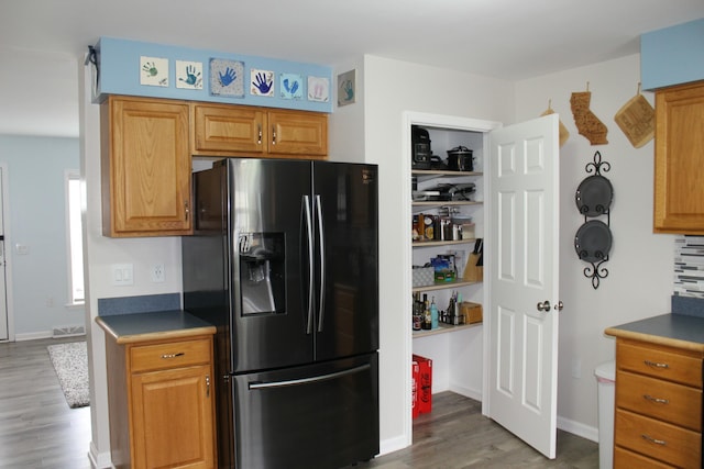 kitchen featuring light wood-style floors, visible vents, black refrigerator with ice dispenser, and baseboards