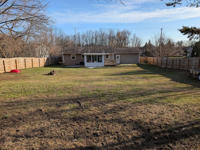 back of house featuring a lawn, a fenced backyard, and a sunroom