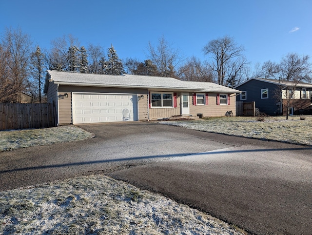 ranch-style home featuring driveway, an attached garage, and fence