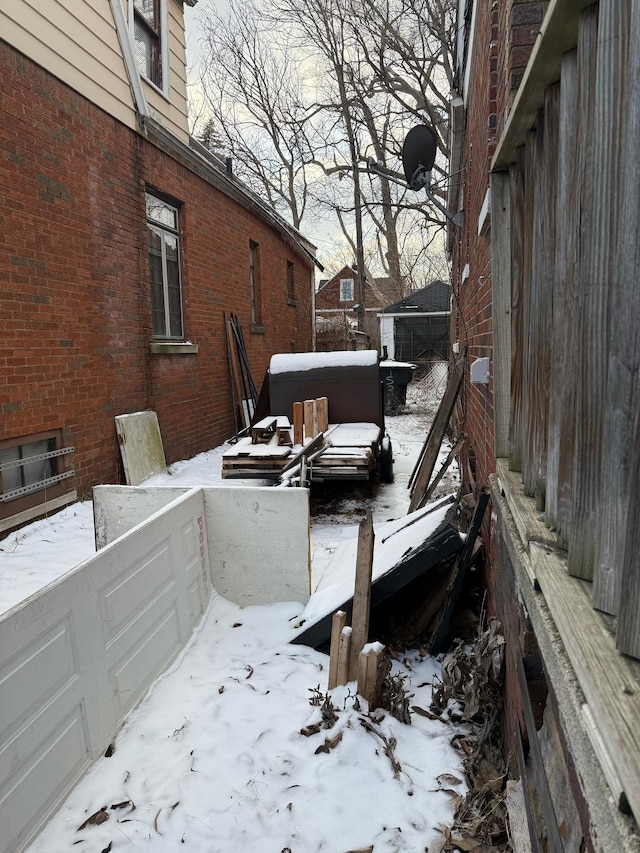 view of snow covered exterior with a garage and brick siding