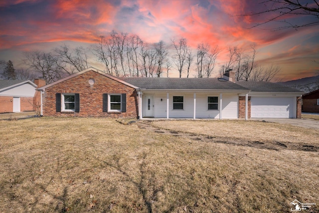 ranch-style house featuring a chimney, concrete driveway, a garage, a lawn, and brick siding