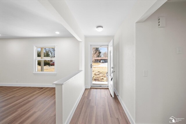 hall with plenty of natural light, baseboards, and wood finished floors