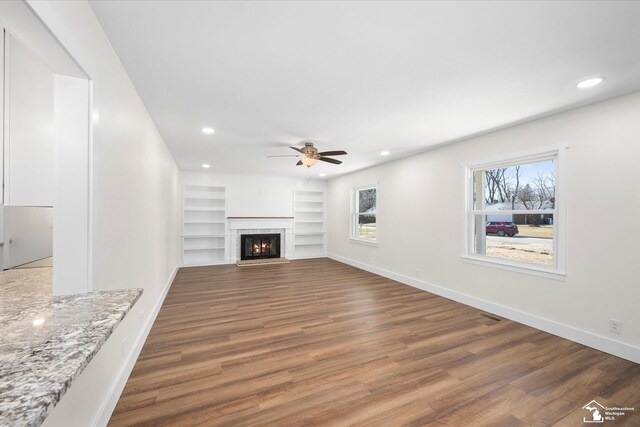 unfurnished living room with recessed lighting, a fireplace, baseboards, and wood finished floors