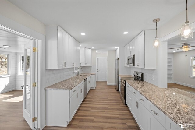 kitchen featuring light stone counters, white cabinetry, stainless steel appliances, and wood finished floors