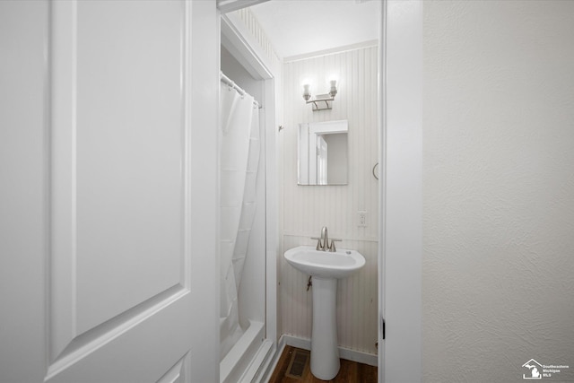 bathroom featuring a textured wall, curtained shower, a sink, and visible vents