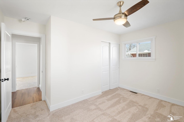 unfurnished room with a ceiling fan, light colored carpet, visible vents, and baseboards