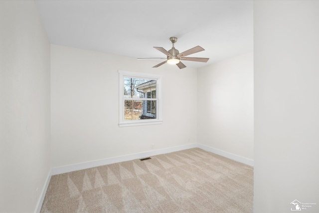 carpeted empty room with baseboards, visible vents, and a ceiling fan