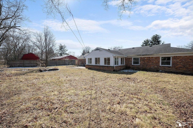 back of property featuring brick siding, a lawn, and fence