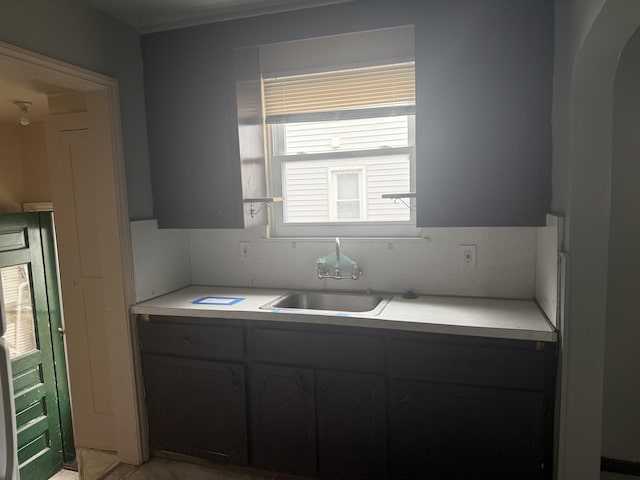 kitchen featuring arched walkways, light countertops, a sink, and refrigerator