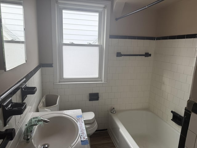 full bath featuring plenty of natural light, a sink, toilet, and tile walls