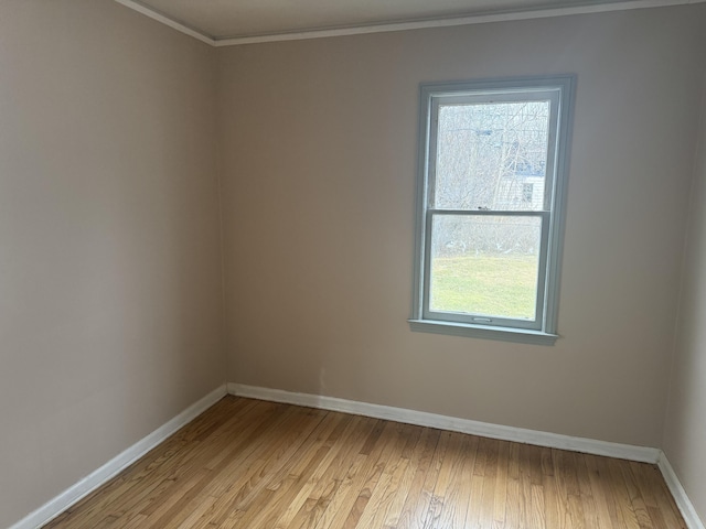 empty room featuring baseboards, ornamental molding, and light wood-style floors