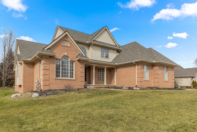 traditional-style house featuring a shingled roof, a front yard, and brick siding