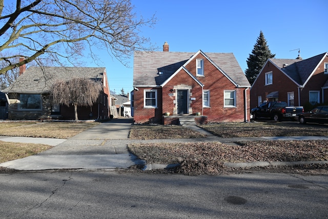 bungalow featuring brick siding and a chimney