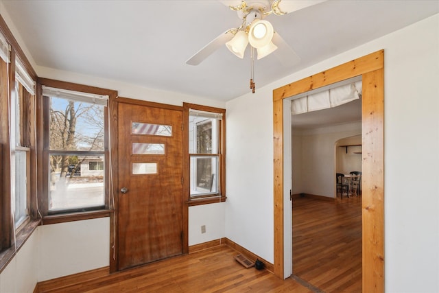 entrance foyer featuring visible vents, baseboards, wood finished floors, arched walkways, and a ceiling fan