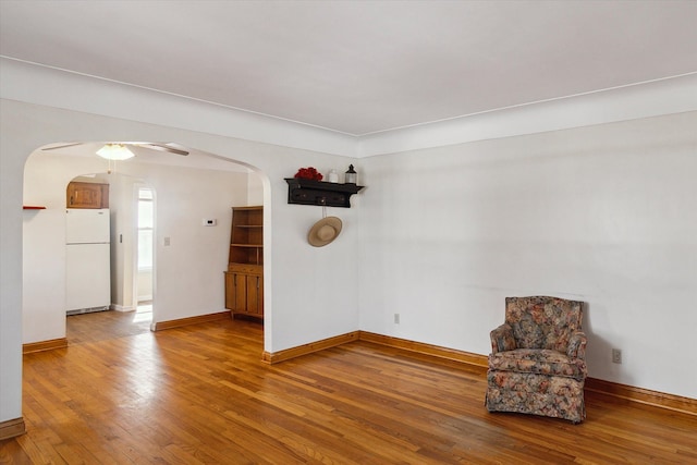 unfurnished room with baseboards, arched walkways, and wood-type flooring