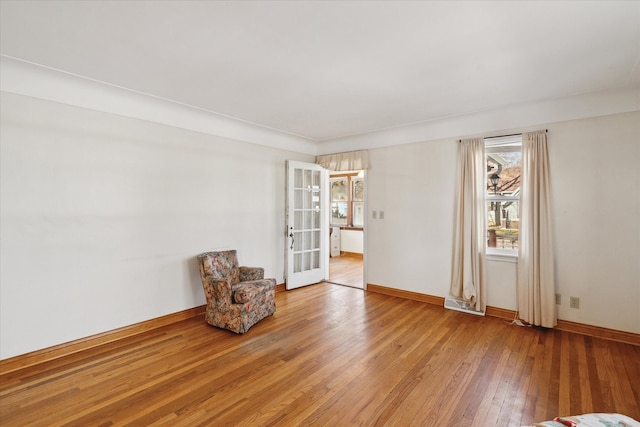 unfurnished room featuring french doors, baseboards, and light wood-style floors