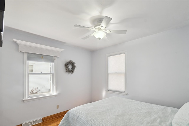 bedroom featuring a ceiling fan, wood finished floors, and visible vents