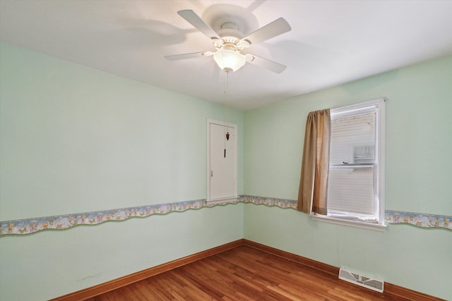 spare room featuring visible vents, baseboards, wood finished floors, and a ceiling fan