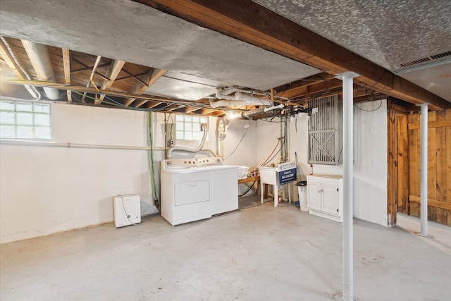 below grade area featuring a sink, visible vents, and washer and clothes dryer