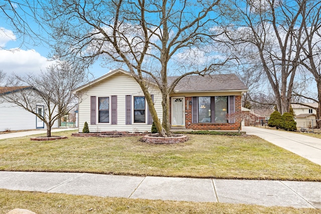 view of front facade featuring brick siding, driveway, a shingled roof, and a front yard