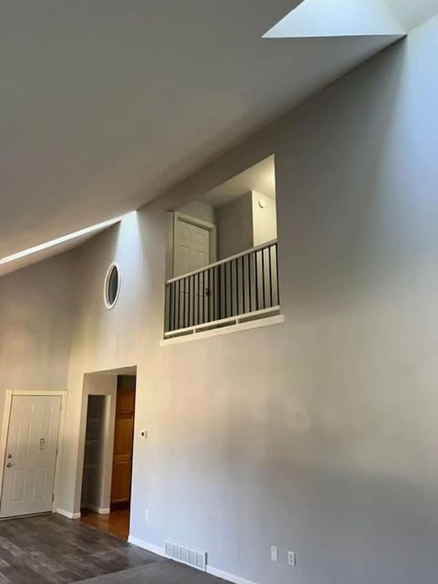 spare room featuring high vaulted ceiling, a skylight, visible vents, and baseboards