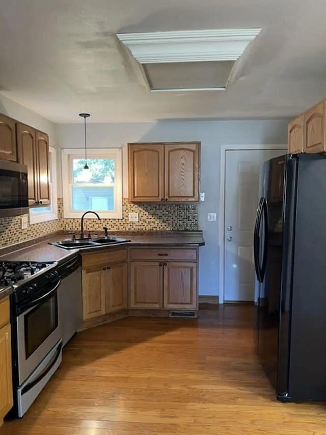 kitchen featuring appliances with stainless steel finishes, dark countertops, light wood-type flooring, and a sink