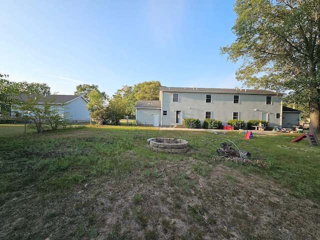 back of property with an outdoor fire pit, a lawn, and fence