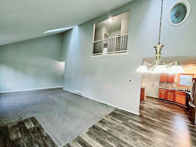 empty room with dark wood finished floors, visible vents, a sink, high vaulted ceiling, and baseboards