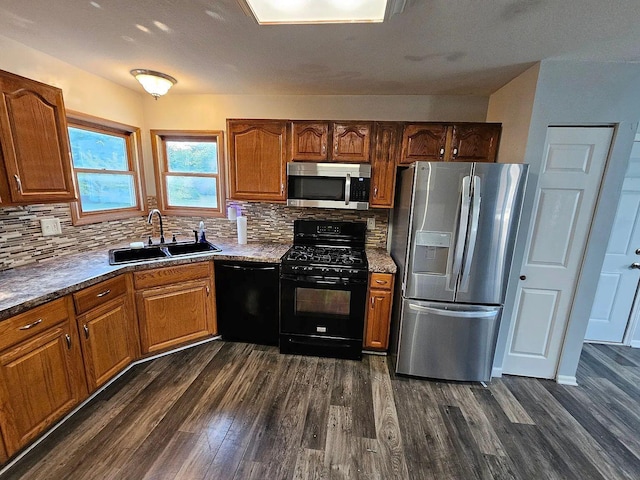 kitchen featuring black appliances, backsplash, dark wood-style flooring, and a sink