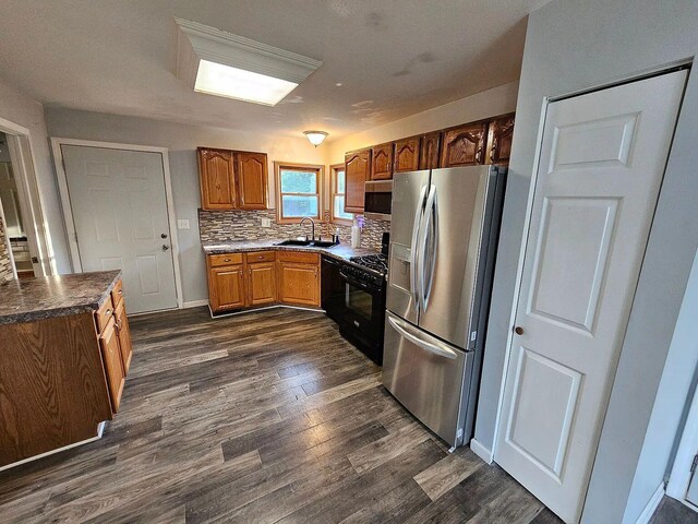 kitchen featuring tasteful backsplash, brown cabinetry, appliances with stainless steel finishes, dark wood-style flooring, and a sink