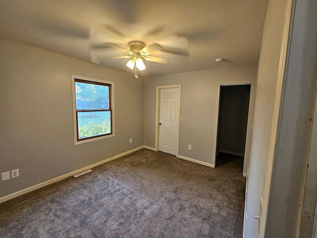 unfurnished bedroom featuring dark colored carpet, visible vents, ceiling fan, a textured ceiling, and baseboards