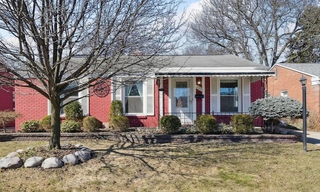 view of front of property with brick siding, covered porch, and a front lawn