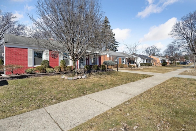 single story home featuring brick siding, a residential view, and a front yard