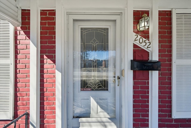 view of exterior entry featuring brick siding