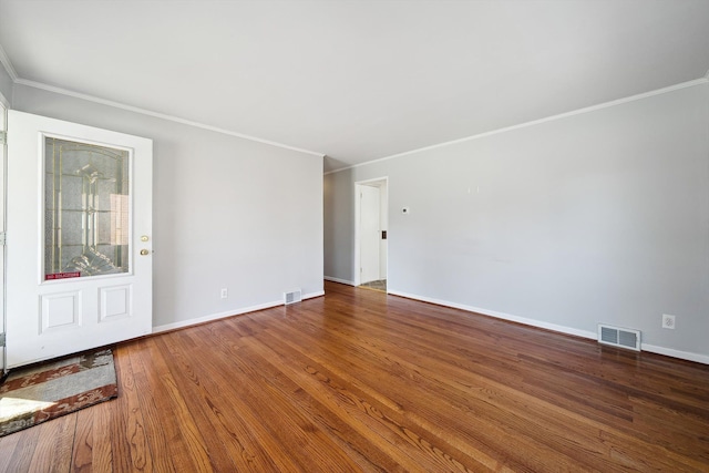 unfurnished room with visible vents, crown molding, baseboards, and wood finished floors