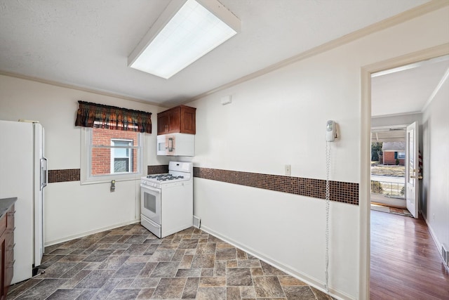 kitchen featuring white appliances, stone finish floor, baseboards, and ornamental molding