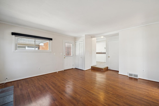 empty room featuring visible vents, ornamental molding, baseboards, and wood finished floors