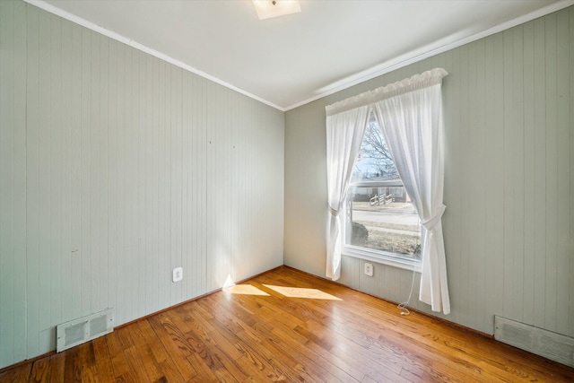 unfurnished room with visible vents, ornamental molding, and hardwood / wood-style flooring