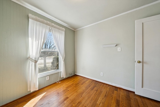 unfurnished room with visible vents, crown molding, baseboards, and wood finished floors