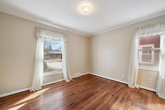 unfurnished room featuring visible vents, wood finished floors, and baseboards