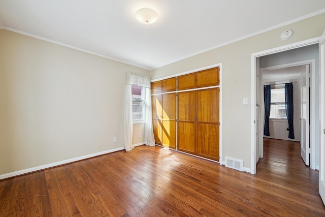 unfurnished bedroom with ornamental molding, wood finished floors, visible vents, and baseboards