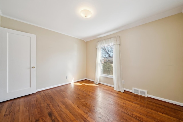 empty room with visible vents, ornamental molding, baseboards, and wood finished floors